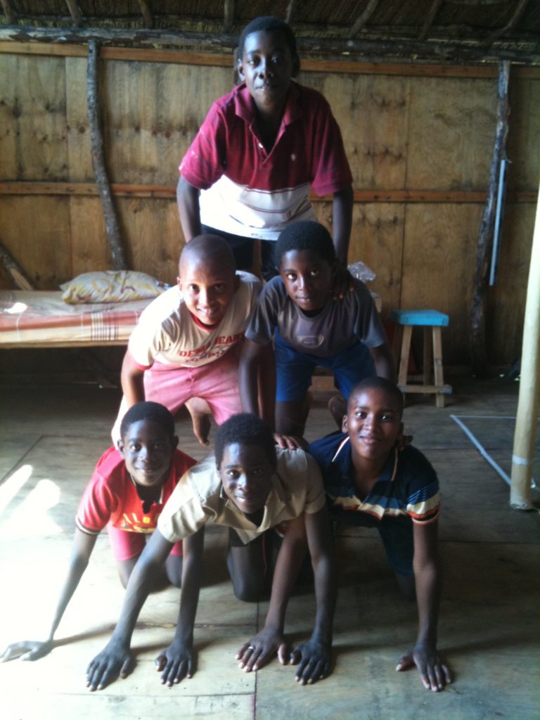 Six boys form a human triangle on all fours.