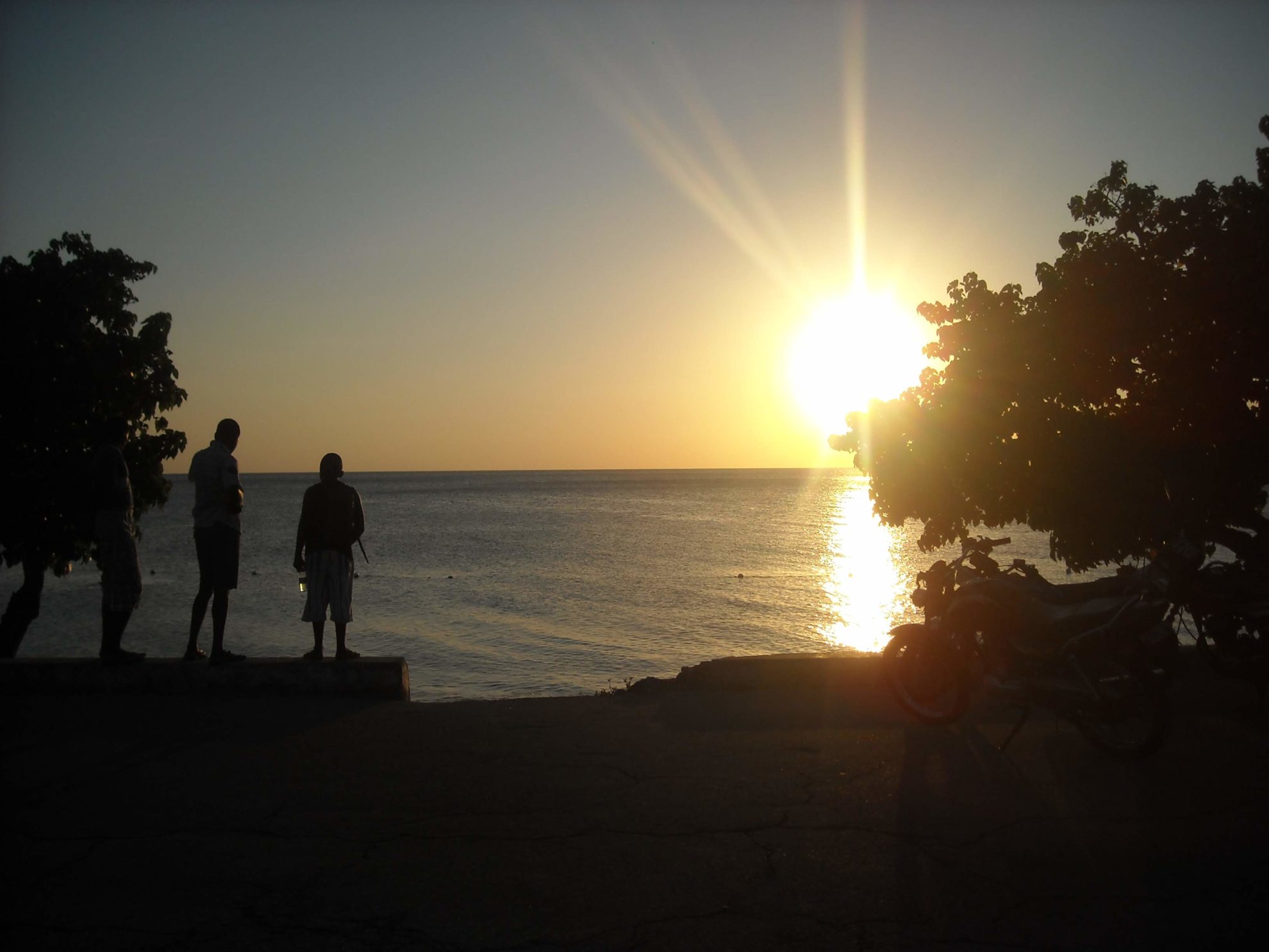 Two silhouetted figures stand in front of an ocean sunset